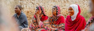 Women and men are sitting on the floor.