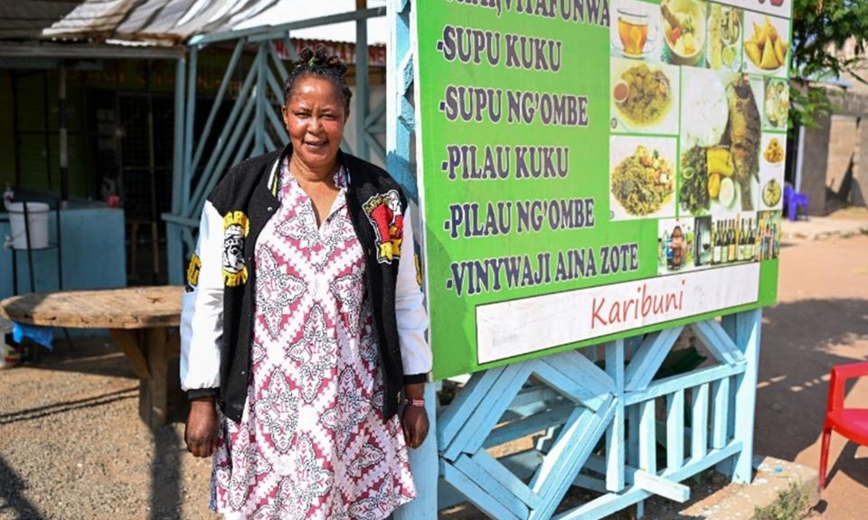 Neema posing in front of her café in Ikungi Market. Photo: UN Women/James Ochweri 