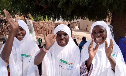 Three women smile and wave